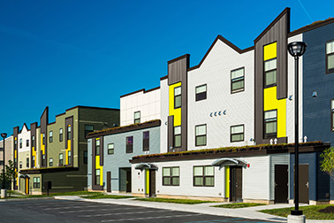 Modern colorful townhouses under clear blue sky.