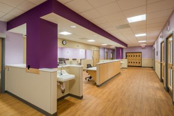 Hospital corridor with purple and beige walls.