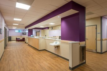 Hospital corridor with purple and beige decor.