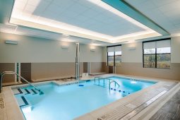 Indoor swimming pool with steps and windows.
