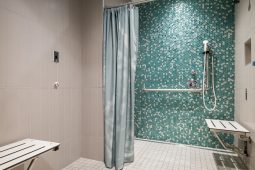 Accessible shower with green mosaic tile wall.