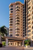 Tall beige apartment building with palm trees.