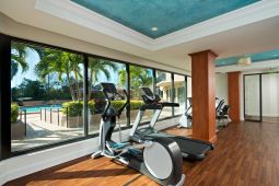 Gym with treadmills overlooking outdoor pool.